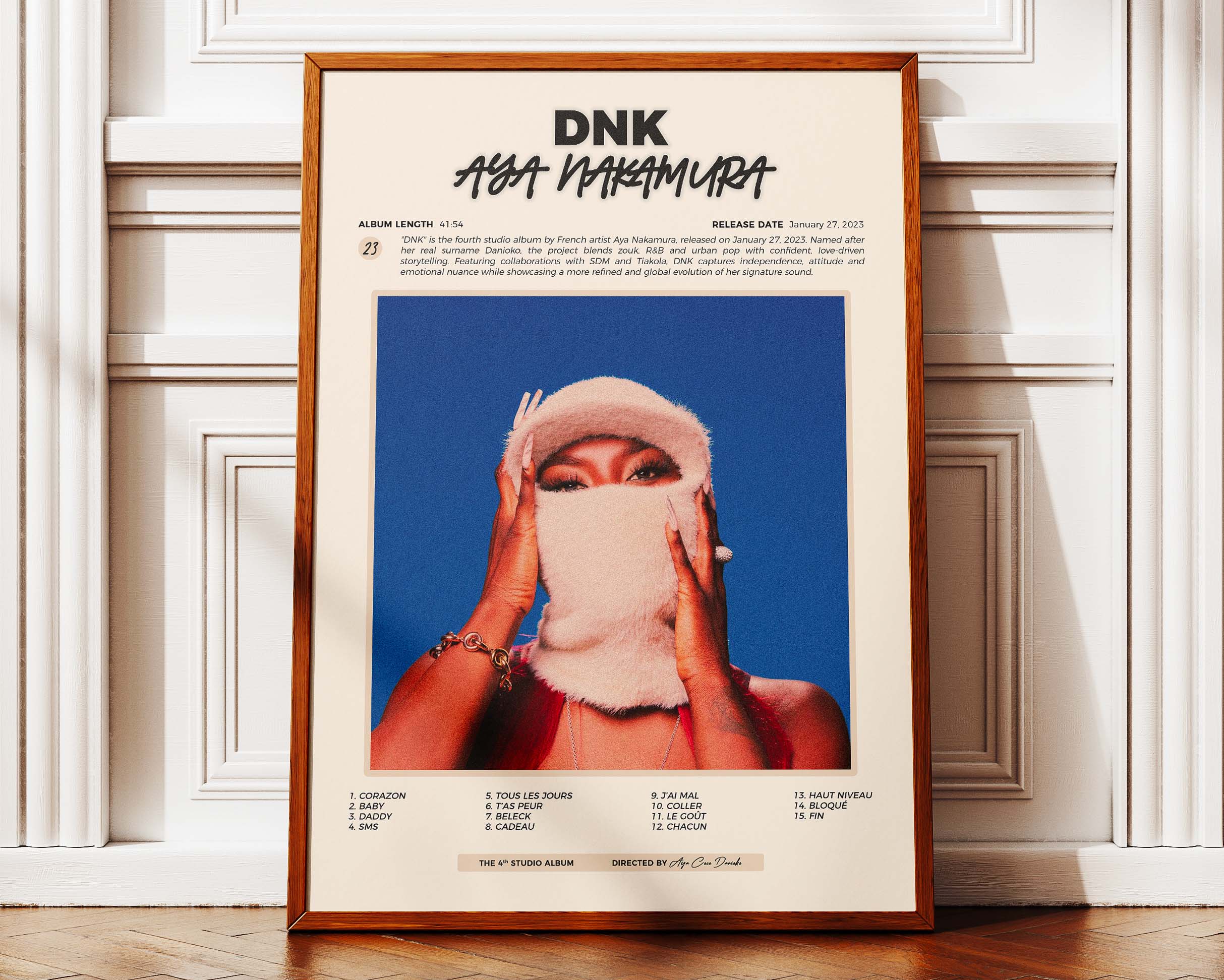 Poster minimaliste encadré de Aya Nakamura DNK posé contre un mur bien visible, décoration moderne et chic.