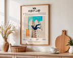 Affiche de Koba LaD accrochée au-dessus d'un buffet en bois, décoration murale harmonieuse avec accessoires de maison naturels et épurés.