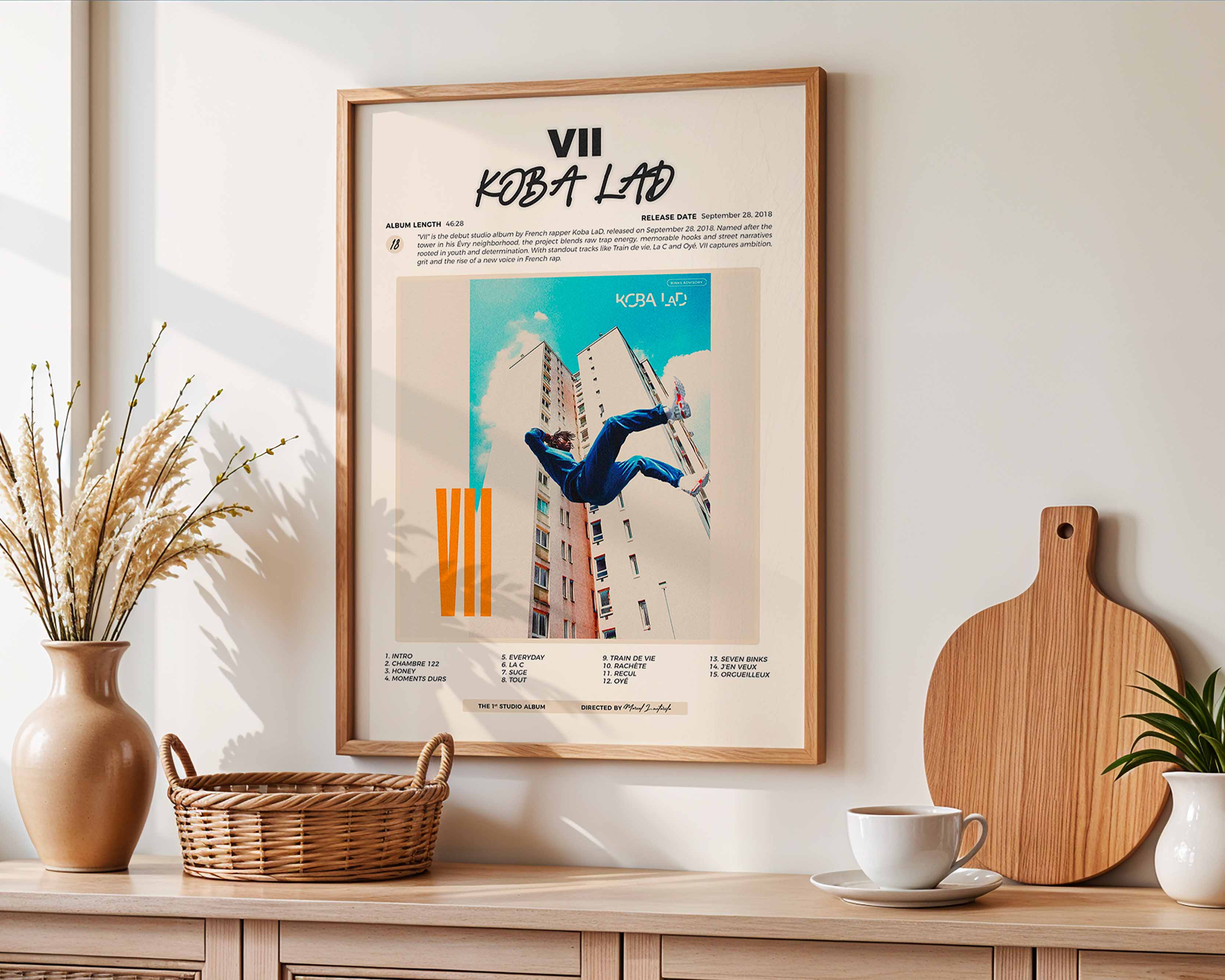 Affiche de Koba LaD accrochée au-dessus d'un buffet en bois, décoration murale harmonieuse avec accessoires de maison naturels et épurés.