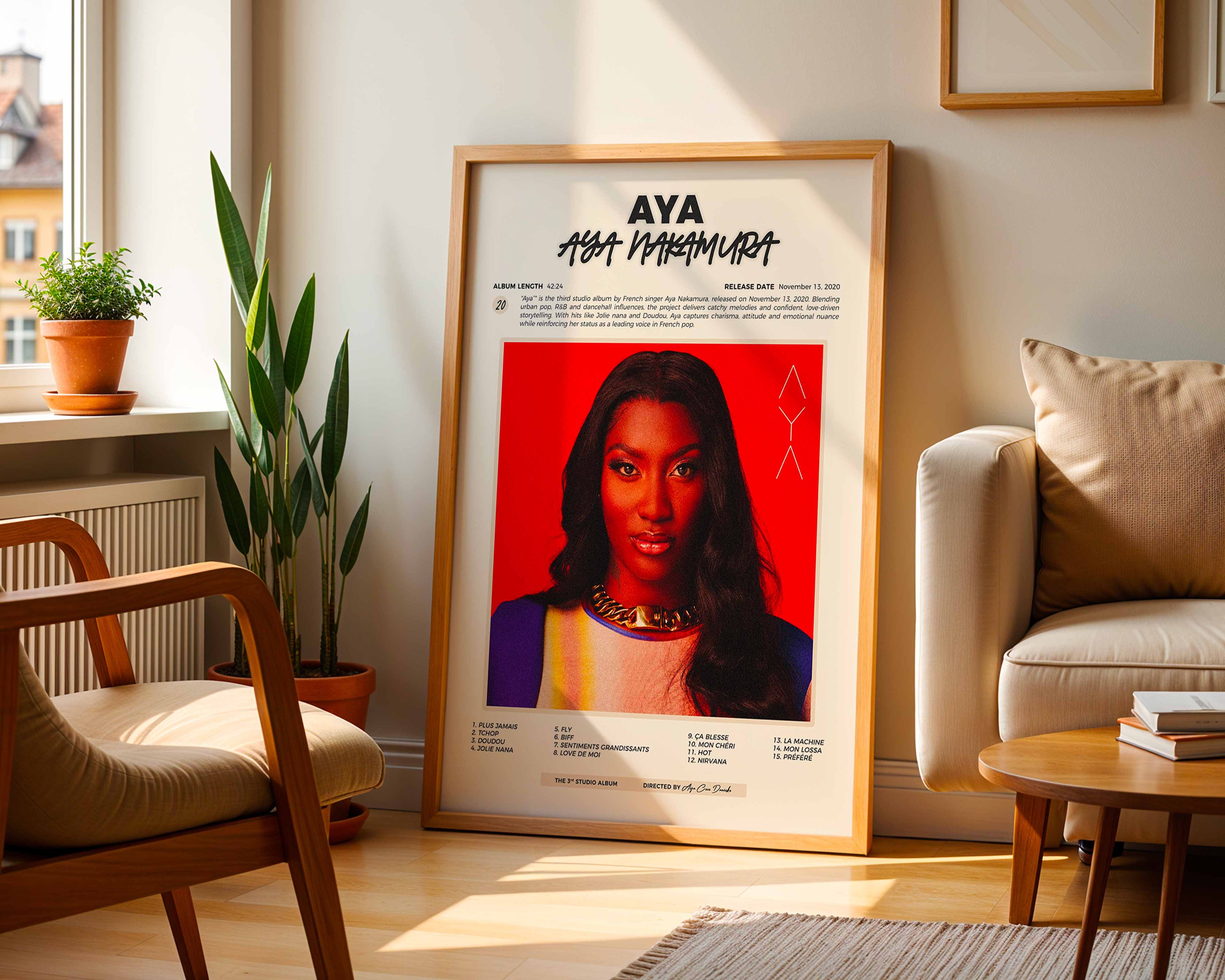 Poster minimaliste encadré de l'album de Aya Nakamura posé contre un mur dans un salon lumineux, art mural contemporain.