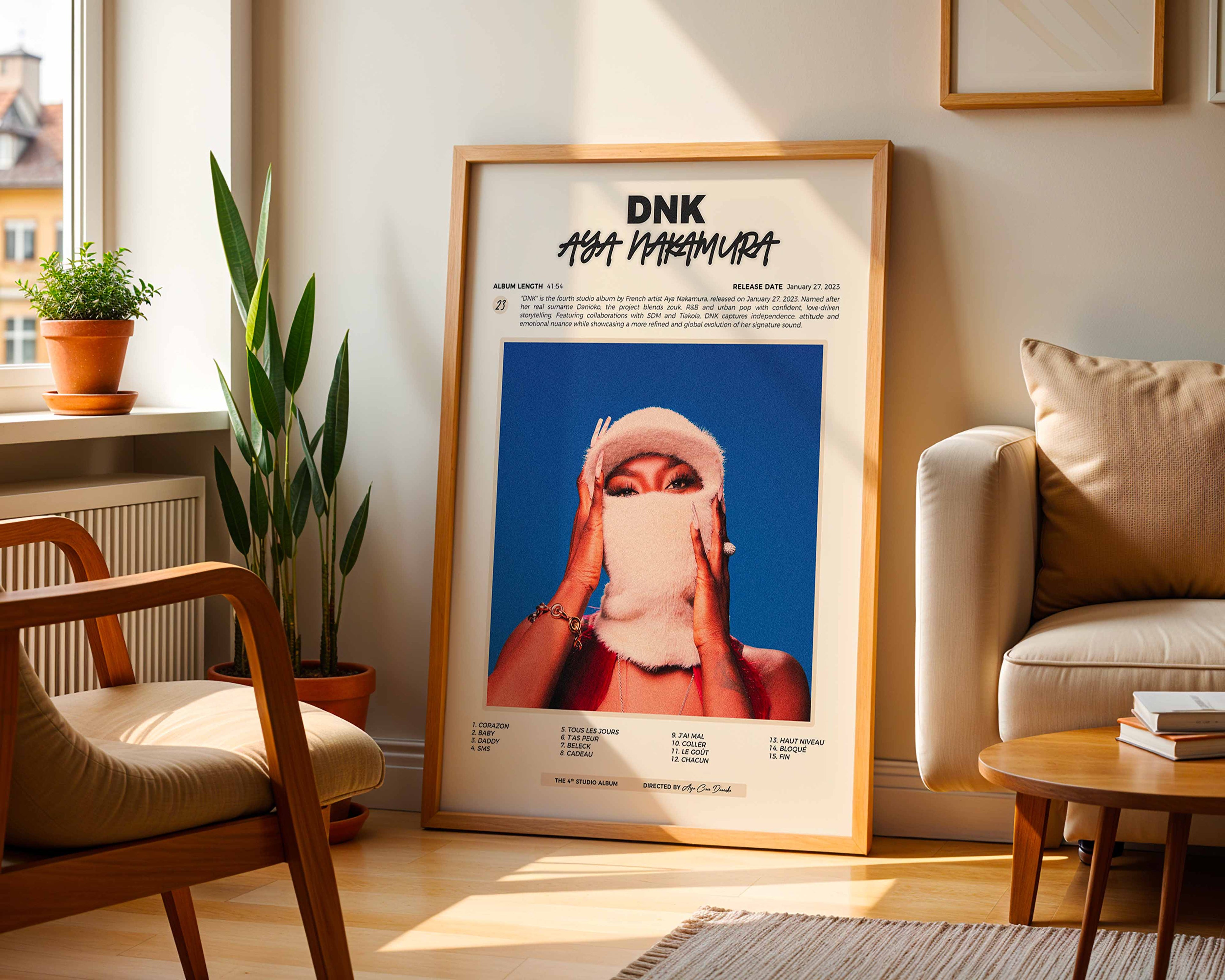 Poster minimaliste encadré de l'album de Aya Nakamura posé contre un mur dans un salon lumineux, art mural contemporain.