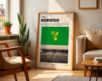 Poster minimaliste du club de Norwich posé contre un mur dans un salon lumineux, art mural Carrow Road.