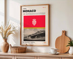 Poster minimaliste de l'AS Monaco accroché au mur dans un salon chic, hommage au Stade Louis-II.