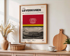 Poster minimaliste du Bayer Leverkusen accroché au mur dans un salon lumineux avec vue sur la BayArena, design premium.
