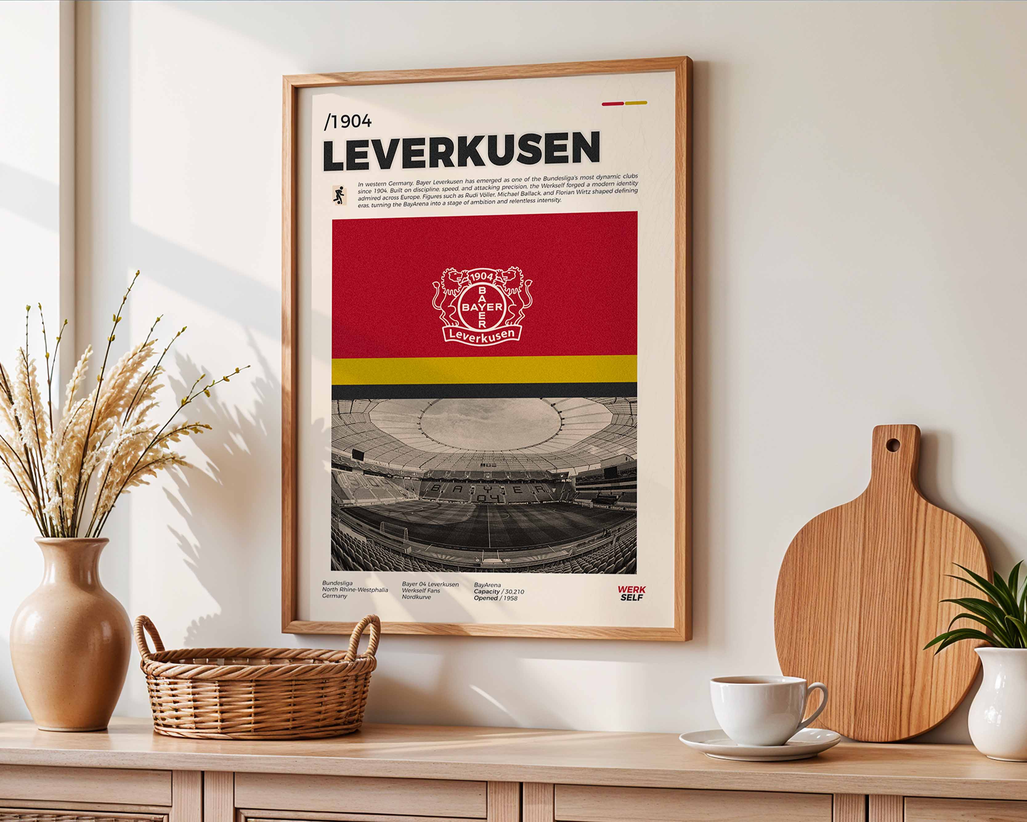 Poster minimaliste du Bayer Leverkusen accroché au mur dans un salon lumineux avec vue sur la BayArena, design premium.