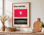 Poster minimaliste encadré de Manchester United accroché au mur dans un salon lumineux et bien visible, design premium rouge.