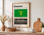Poster minimaliste de Norwich City accroché au mur dans un salon, hommage authentique au stade Carrow Road.