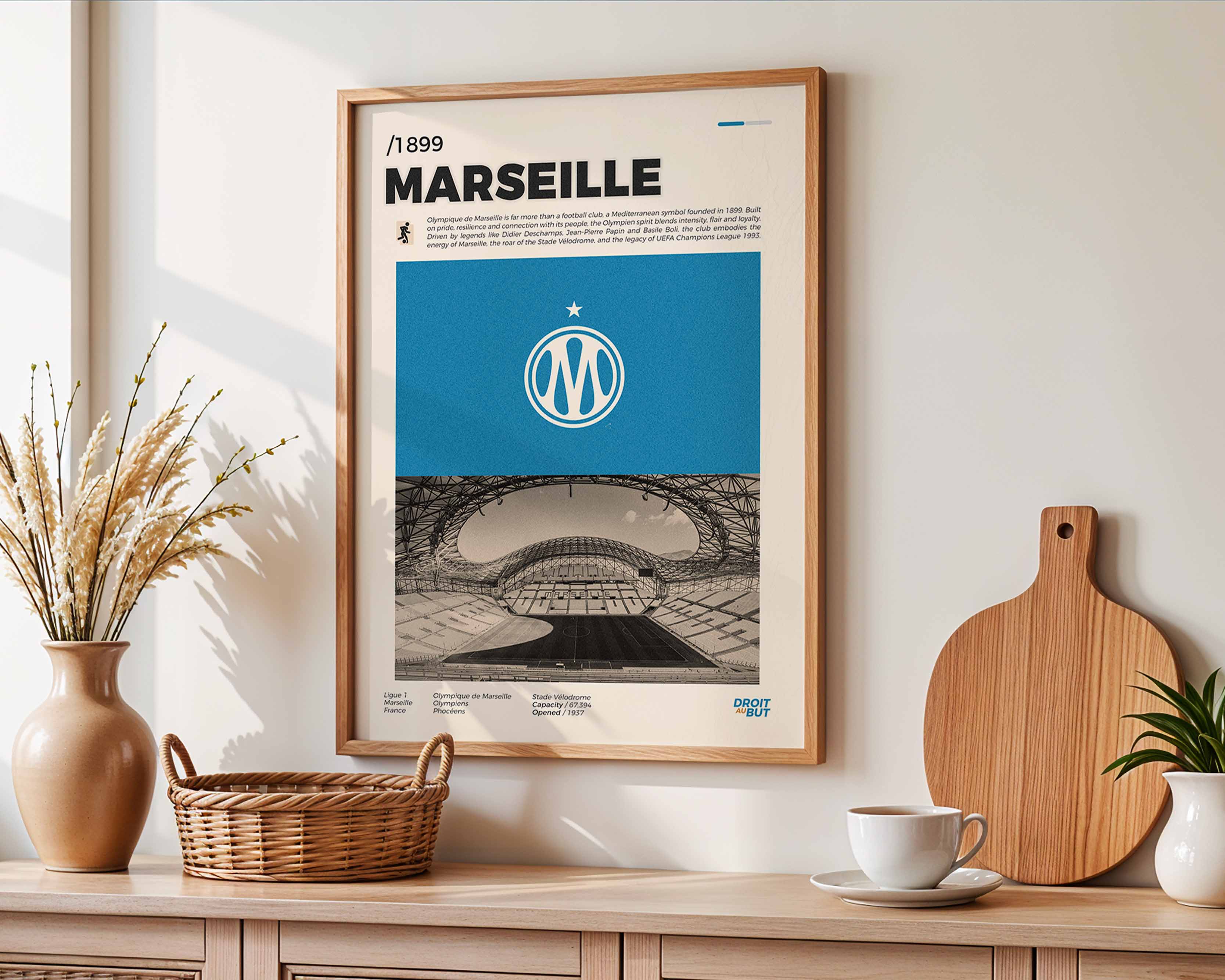 Poster minimaliste encadré de l'Olympique de Marseille accroché au mur dans un salon lumineux et bien visible, design premium bleu ciel.