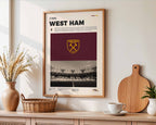 Poster minimaliste de West Ham accroché au mur dans un salon, hommage architectural au London Stadium.