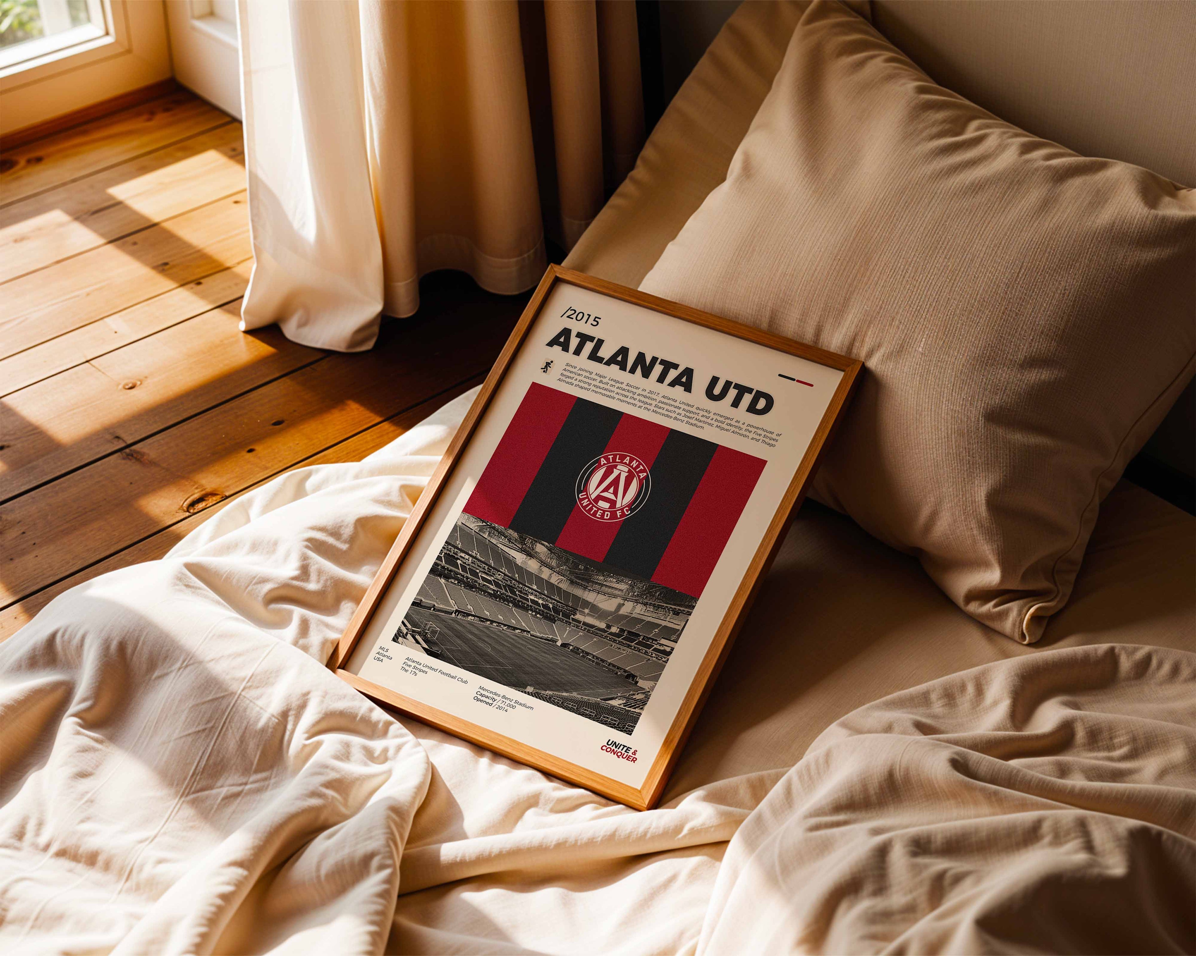 Poster minimaliste encadré de Atlanta United posé sur un lit dans une chambre, idée cadeau fan de soccer.