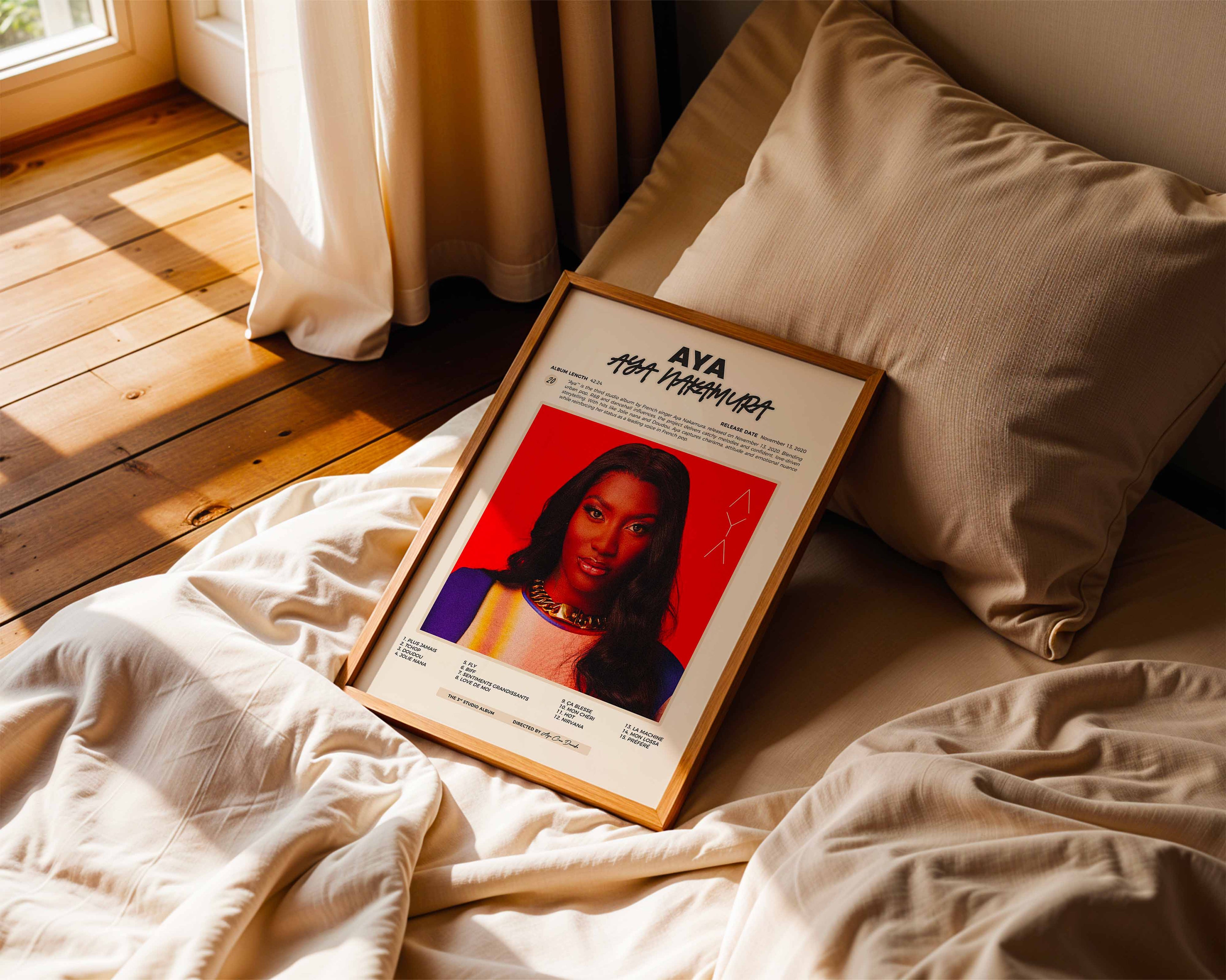 Poster minimaliste encadré de Aya Nakamura Aya posé sur un lit dans une chambre, idée cadeau fan de pop urbaine.
