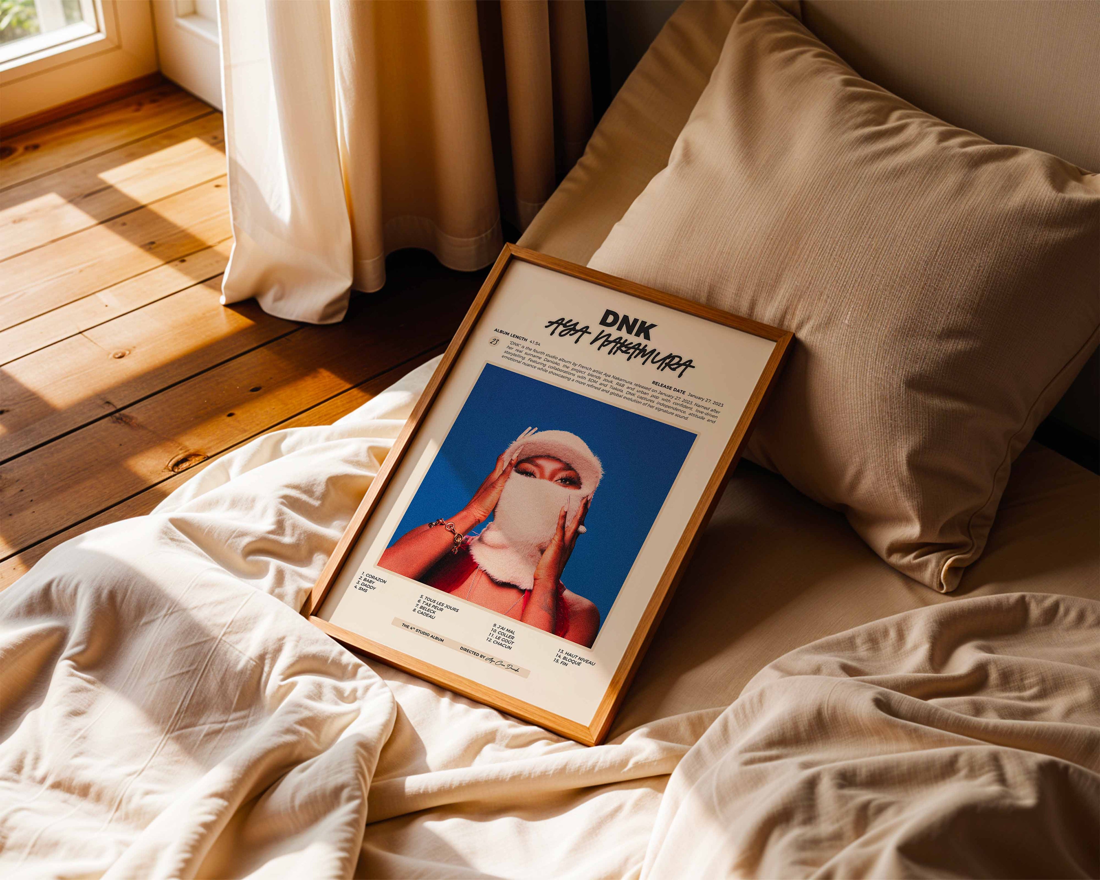 Poster minimaliste encadré de Aya Nakamura DNK posé sur un lit dans une chambre, idée cadeau fan d'Aya.