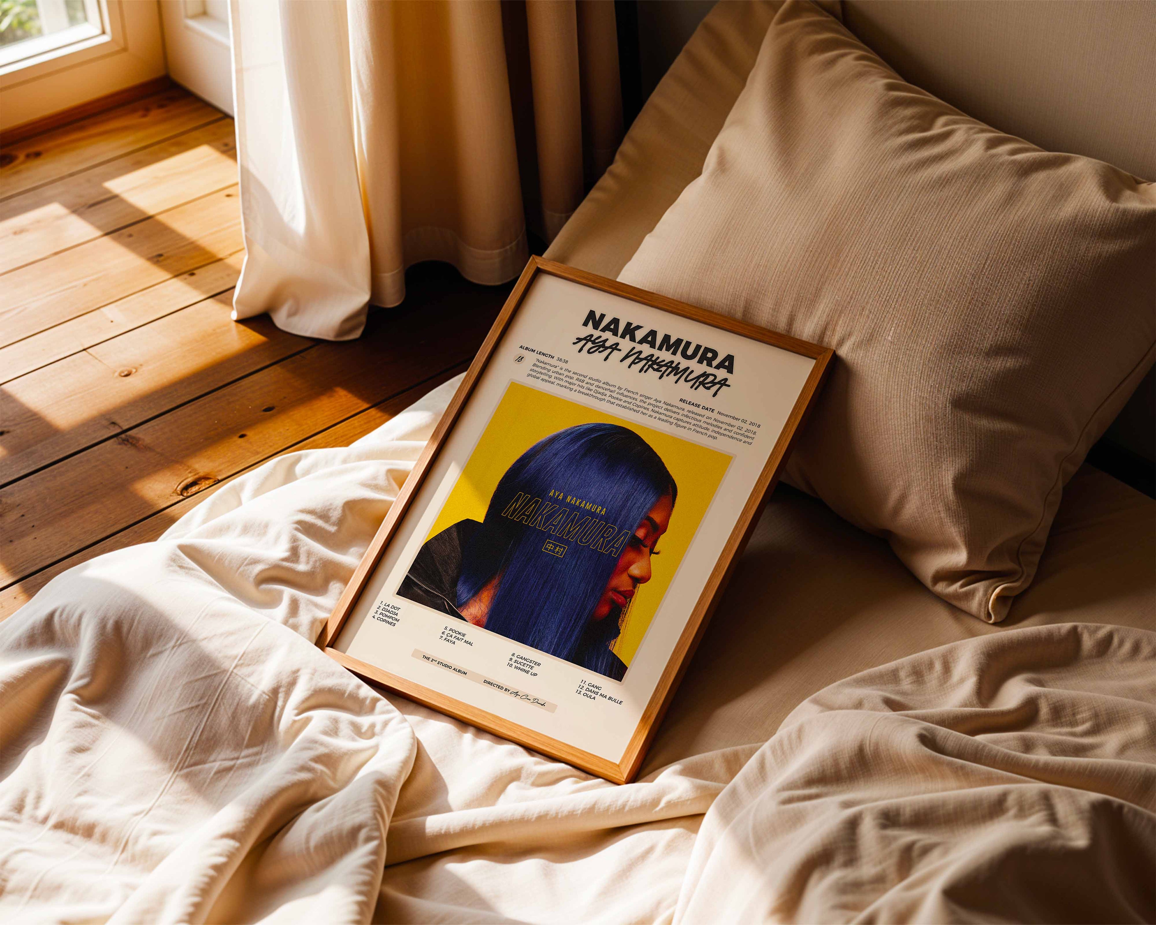 Poster minimaliste encadré de Aya Nakamura Nakamura posé sur un lit dans une chambre, idée cadeau fan de musique.