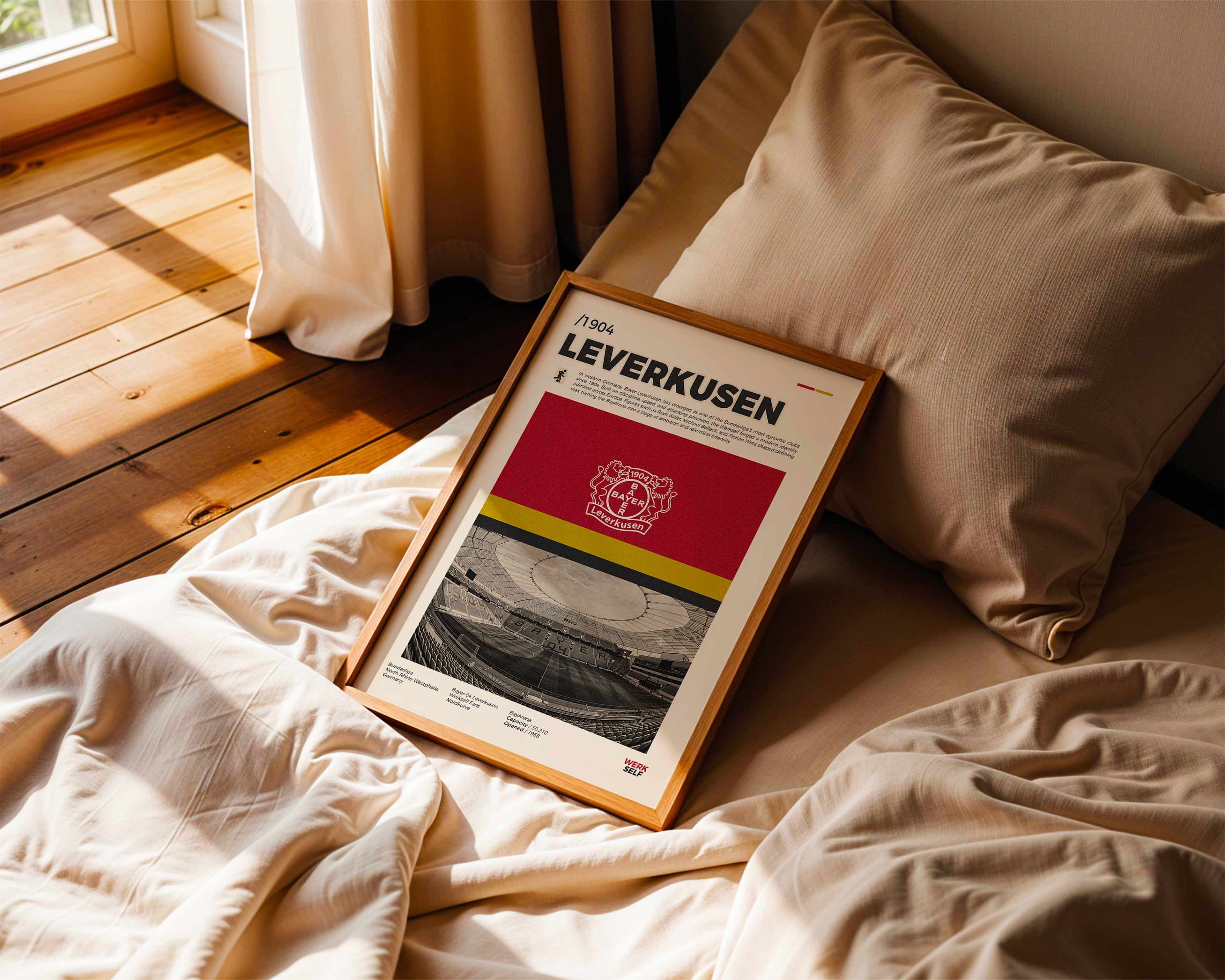 Poster minimaliste du Bayer Leverkusen posé sur un lit dans une chambre, idée cadeau fan de la BayArena.