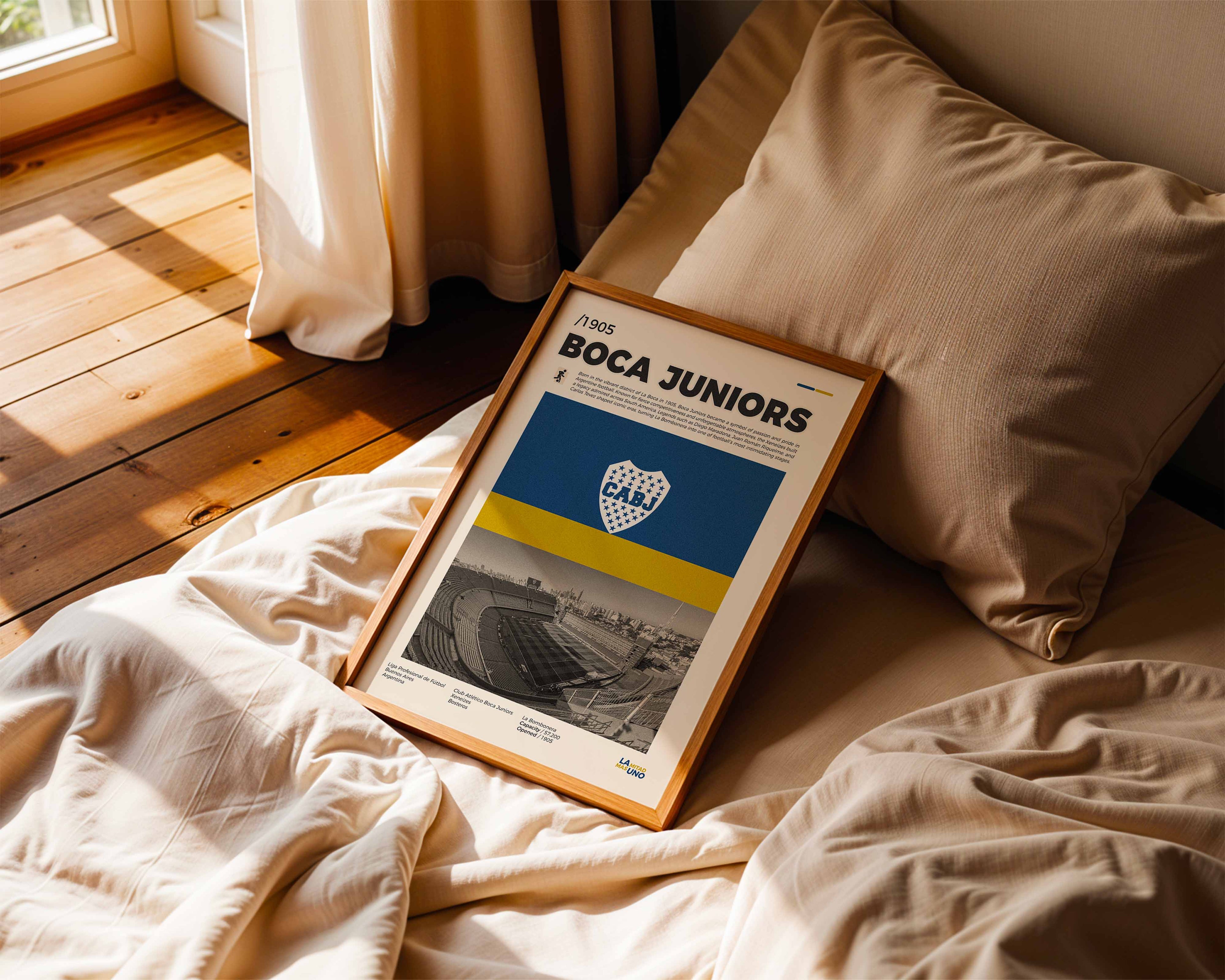 Poster minimaliste encadré de Boca Juniors posé sur un lit dans une chambre, idée cadeau fan du football sud-américain.