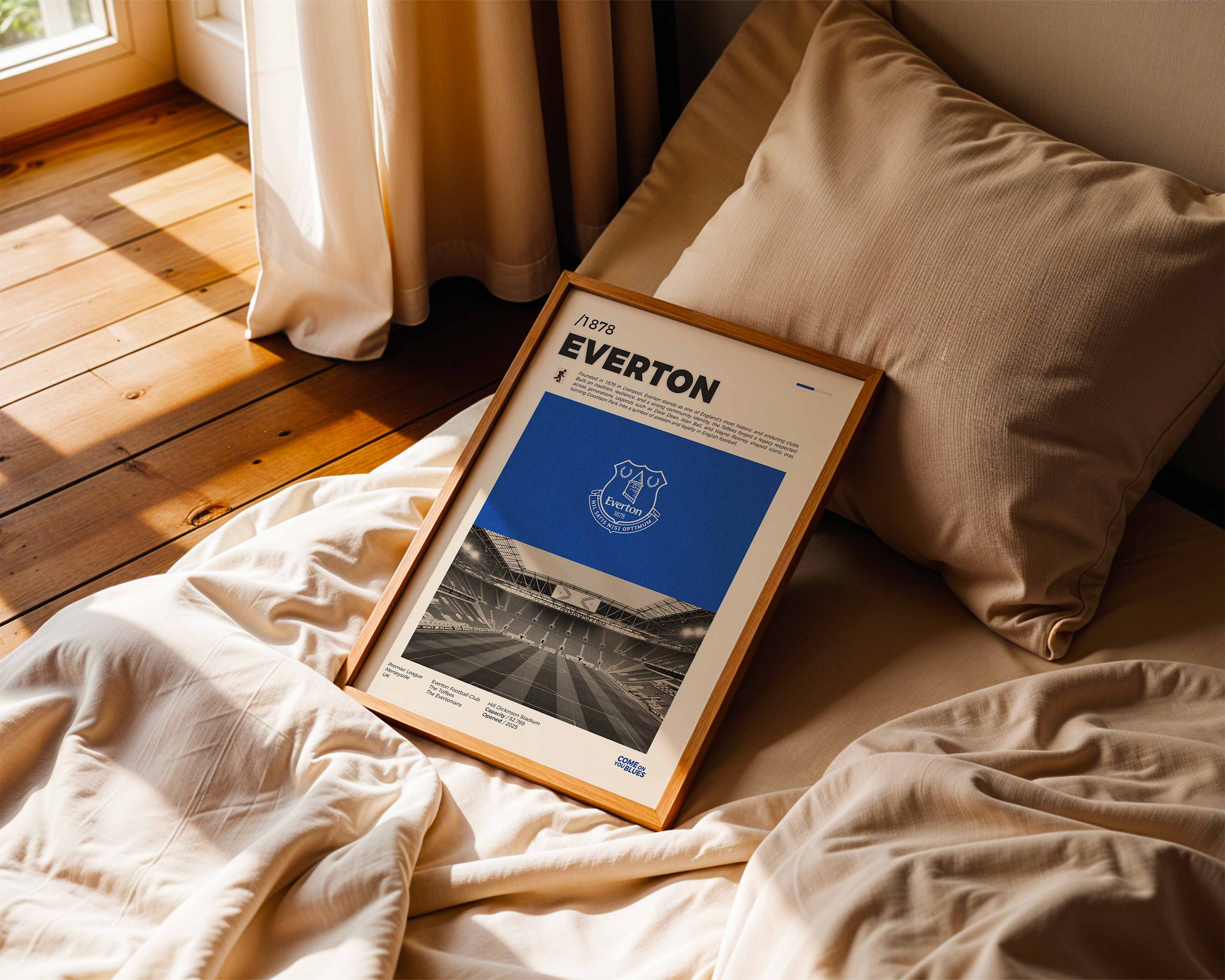 Poster minimaliste encadré d'Everton posé sur un lit dans une chambre, idée cadeau pour un supporter des Toffees.