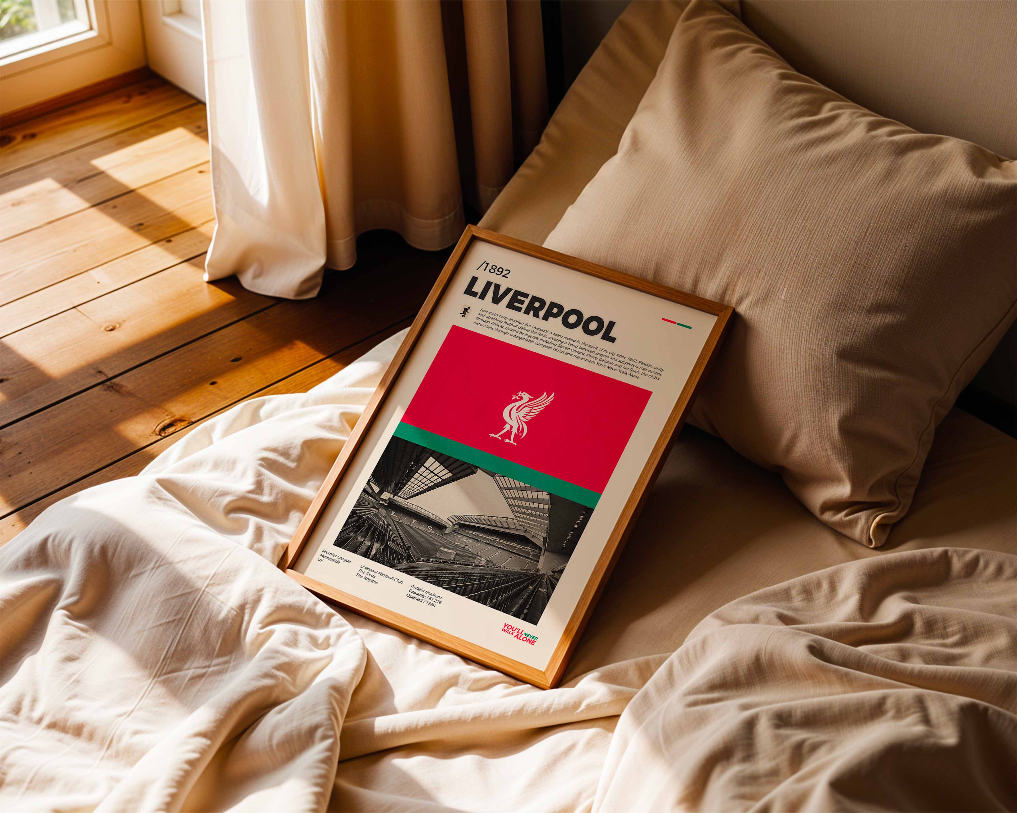 Poster minimaliste de Liverpool posé sur un lit dans une chambre, idée cadeau fan du stade Anfield.