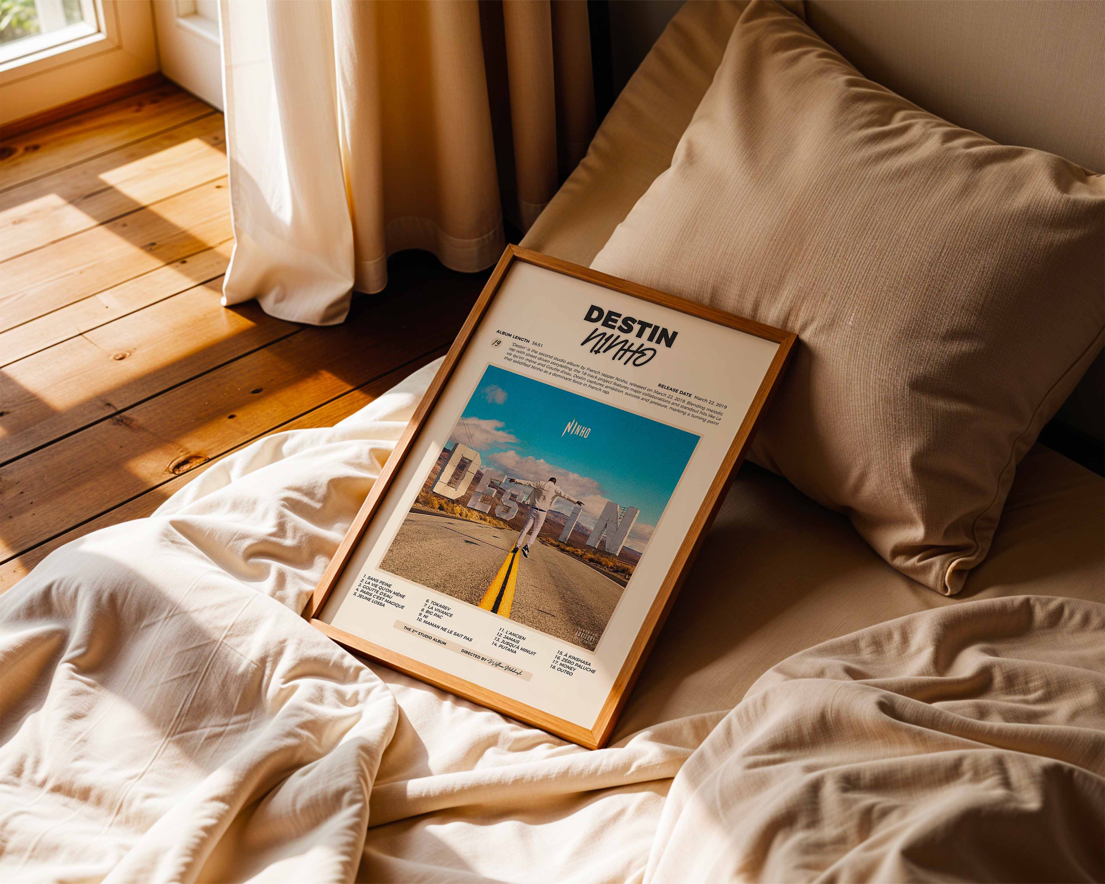 Poster minimaliste encadré de Ninho Destin posé sur un lit dans une chambre, idée cadeau fan de NI.