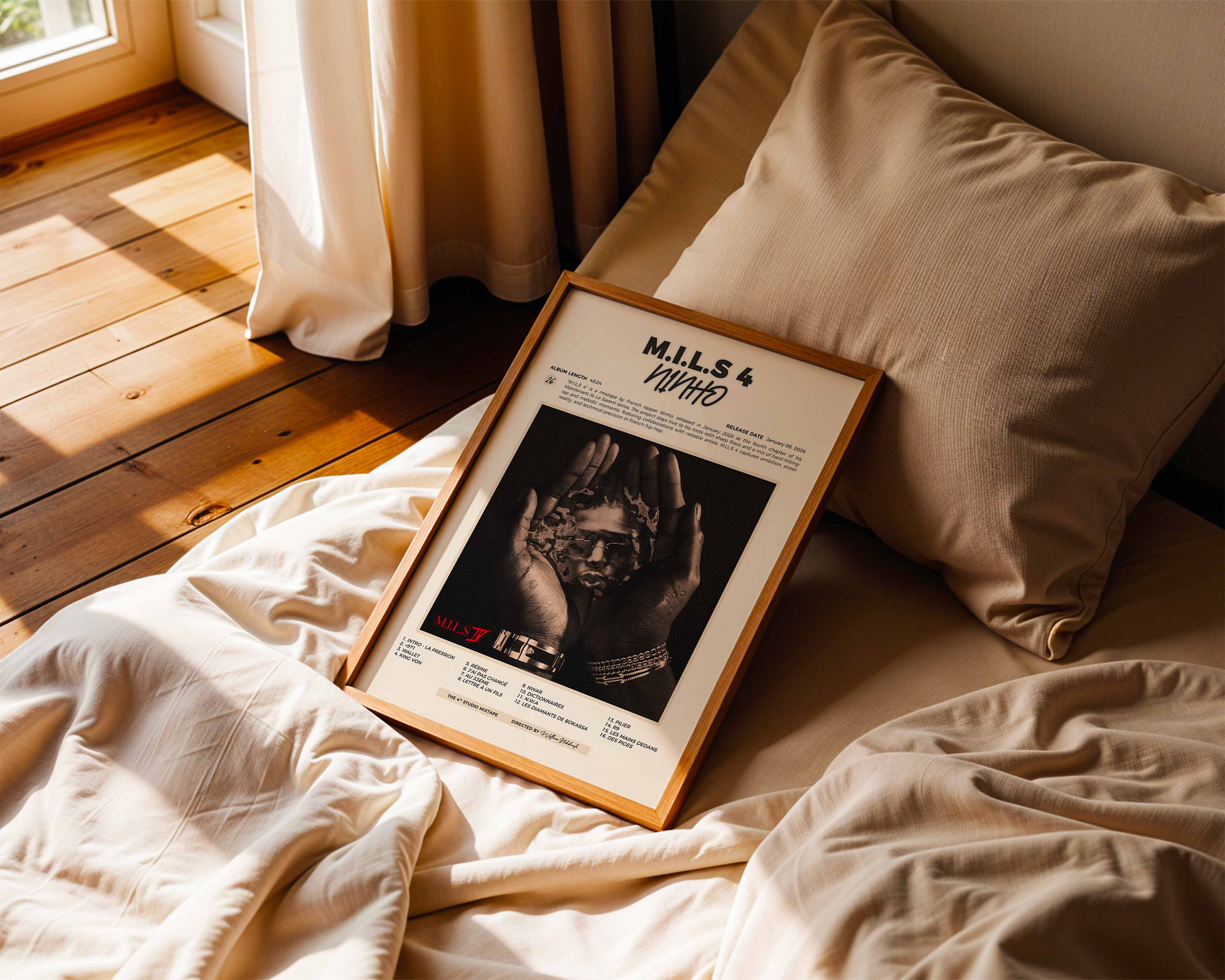 Poster minimaliste encadré de Ninho M.I.L.S 4 posé sur un lit dans une chambre, idée cadeau fan de Ninho.