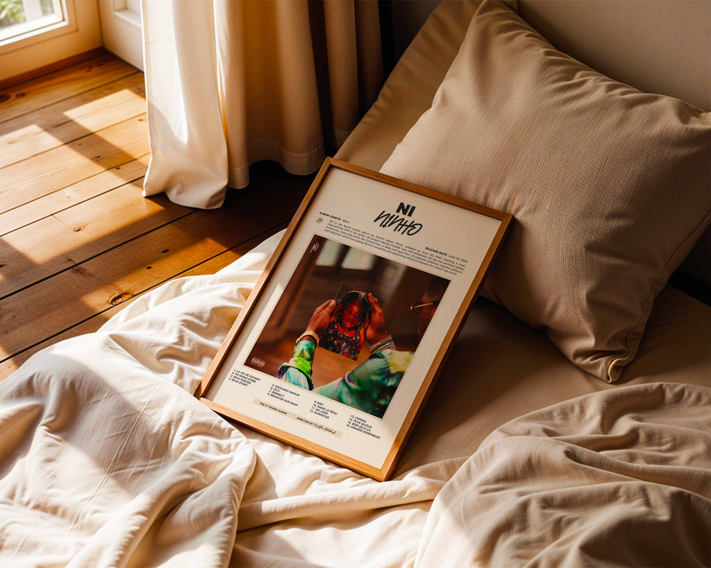 Poster minimaliste encadré de Ninho NI posé sur un lit dans une chambre, idée cadeau fan de NI.
