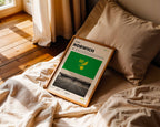 Poster minimaliste de Norwich City posé sur un lit dans une chambre, idée cadeau fan de Carrow Road.