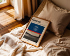 Poster minimaliste encadré du PSG posé sur un lit dans une chambre, idée cadeau fan de football Paris.