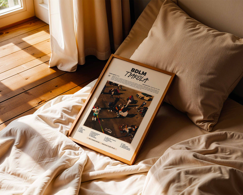 Poster minimaliste encadré de Tiakola BDLM Vol. 1 posé sur un lit dans une chambre, idée cadeau fan de Tiakola.